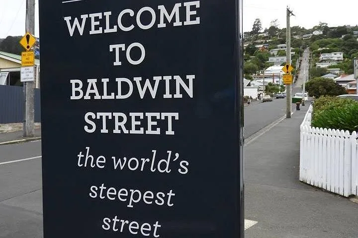 A sign reading 'Welcome to Baldwin Street the world's steepest street'.